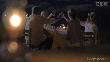 夜晚，一家人围坐在户外的桌子旁，碰杯聊天